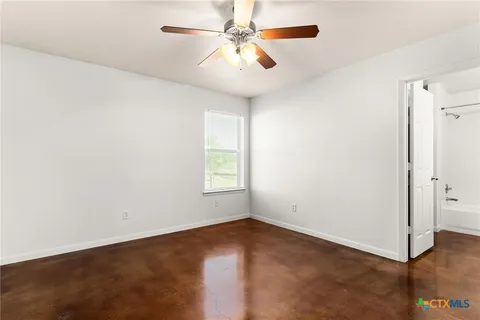 an empty room with windows and fan