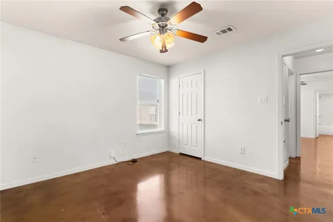 an empty room with windows and fan