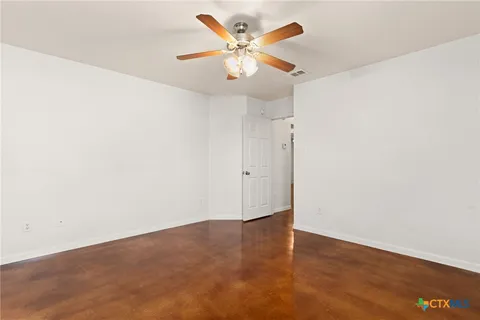 an empty room with wooden floor and ceiling fan
