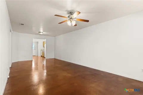 a view of an empty room with window and wooden floor