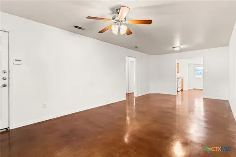 a view of an empty room with window and wooden floor