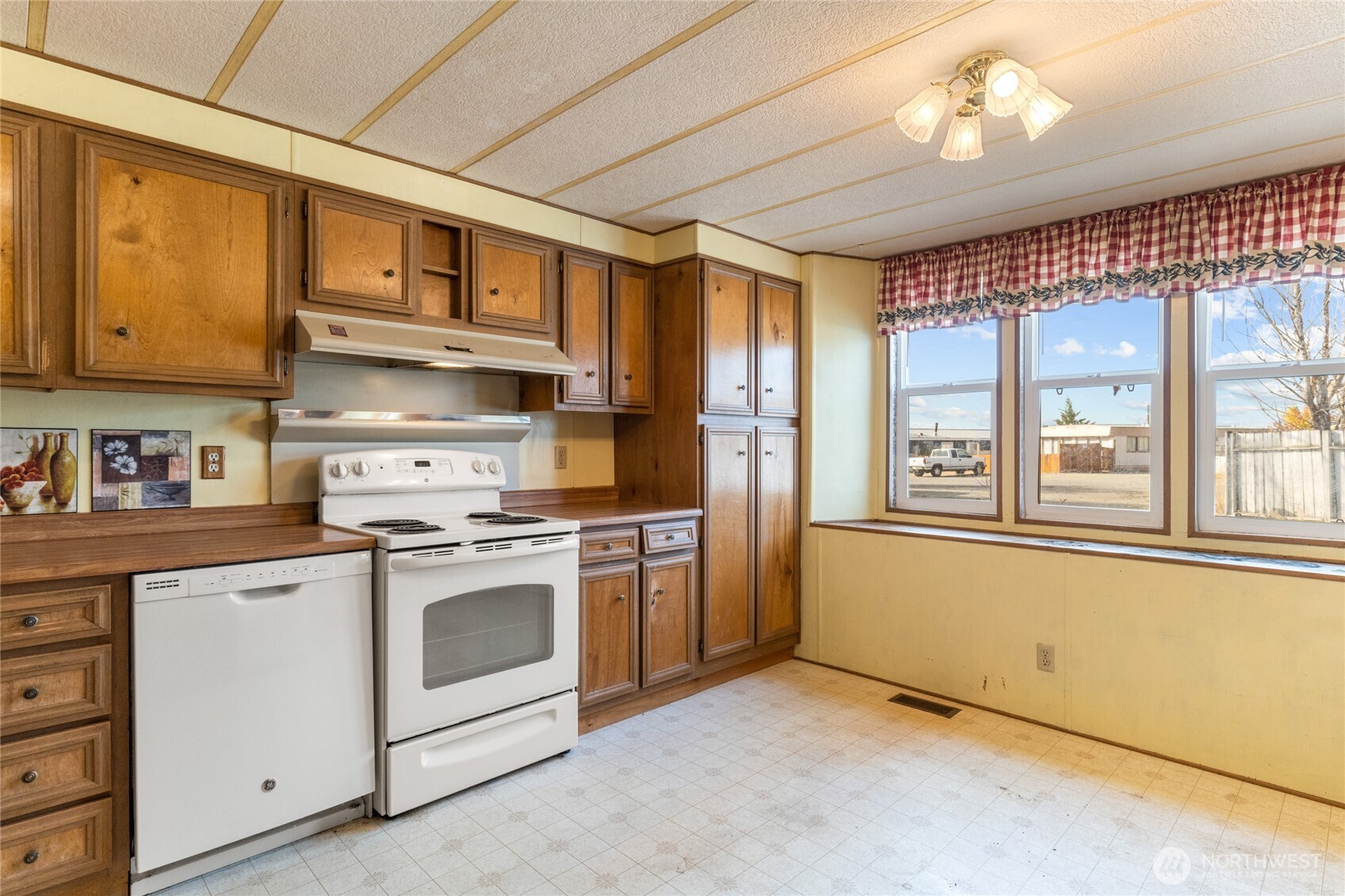 52 Engh Road, Unit 17B Omak, WA 98841 - Photo 11 of 27 a kitchen with stainless steel appliances granite countertop a stove a sink dishwasher and a refrigerator with wooden cabinets