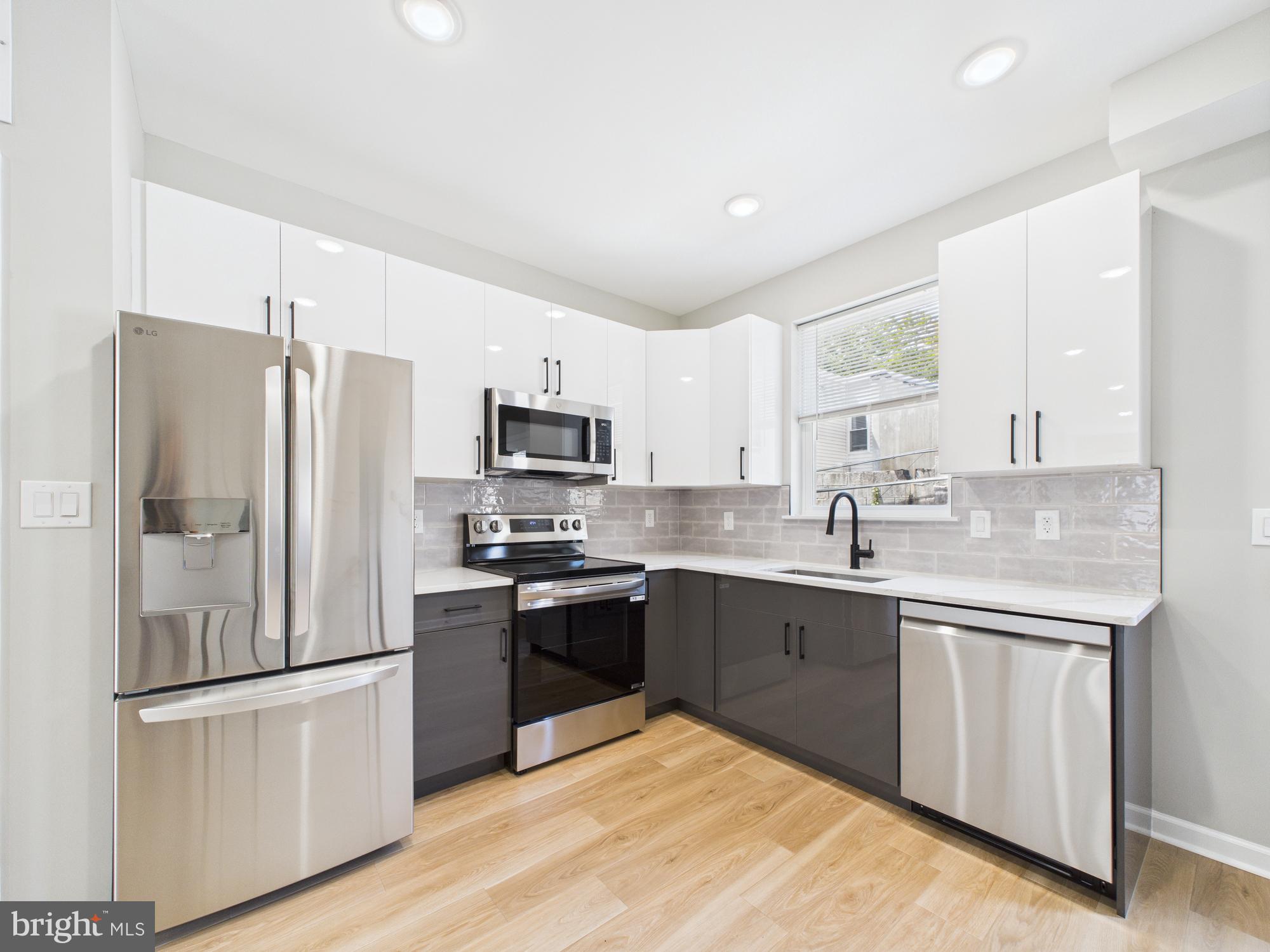 1320 Grove Street, Unit 1 Philadelphia, PA 19146 - Photo 9 of 15 a kitchen with stainless steel appliances granite countertop a stove a sink dishwasher a refrigerator and white cabinets with wooden floor