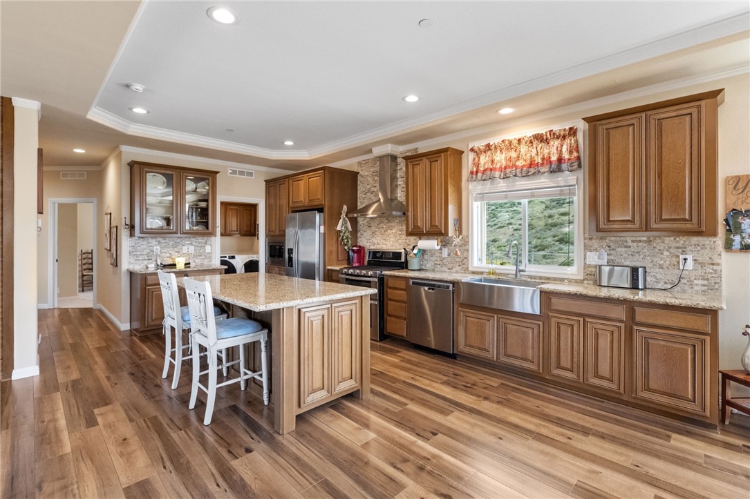 46430 De Portola Road Temecula, CA 92592 - Photo 13 of 61 a kitchen with stainless steel appliances granite countertop a stove top oven a sink dishwasher and a refrigerator with wooden floor