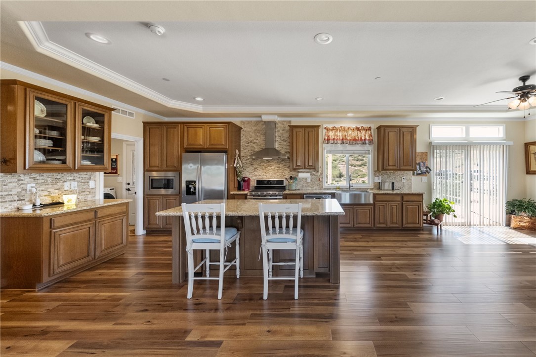 46430 De Portola Road Temecula, CA 92592 - Photo 14 of 61 a kitchen with stainless steel appliances granite countertop a stove top oven a sink a dining table and chairs