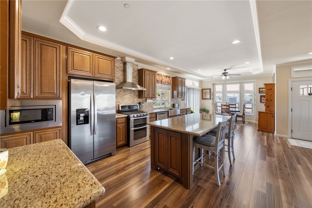 46430 De Portola Road Temecula, CA 92592 - Photo 15 of 61 a kitchen with stainless steel appliances granite countertop a refrigerator a stove top oven a sink dishwasher and a dining table with wooden floor