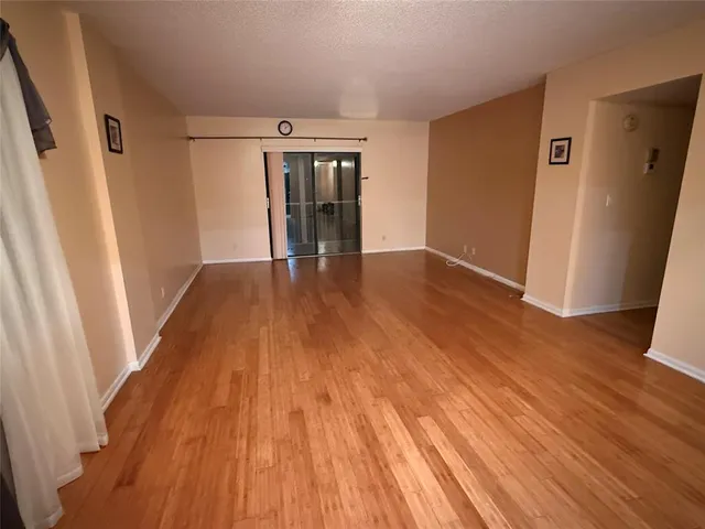 a view of a room with wooden floor and a ceiling fan