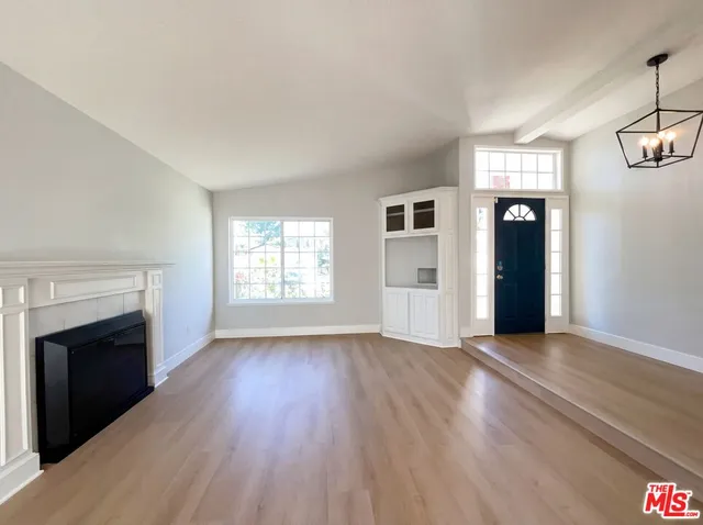 an empty room with wooden floor fireplace and windows