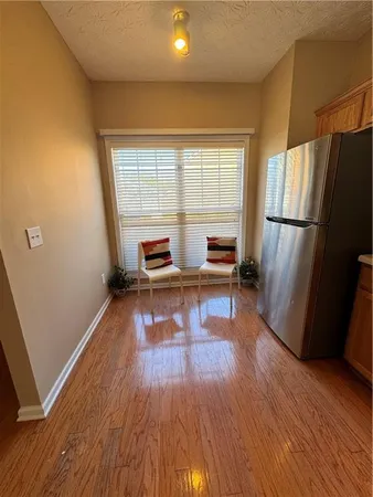 a living room with stainless steel appliances furniture refrigerator and a wooden floor