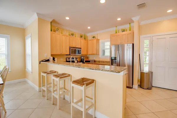 a kitchen with stainless steel appliances granite countertop a stove top oven a sink dishwasher and a refrigerator with wooden floor