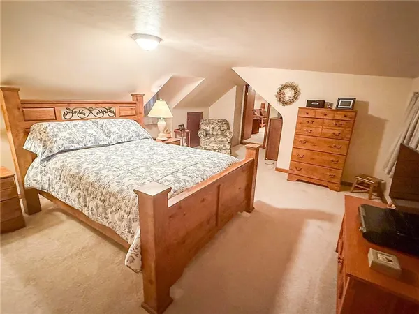 a spacious bedroom with a bed and a flat tv screen on a dresser