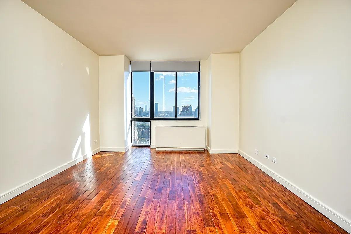 255 East 49th Street, Unit 31C Manhattan, NY 10017 - Photo 8 of 11 an empty room with wooden floor and windows