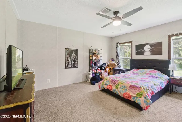 a bedroom with a bed a dresser and painting on the wall