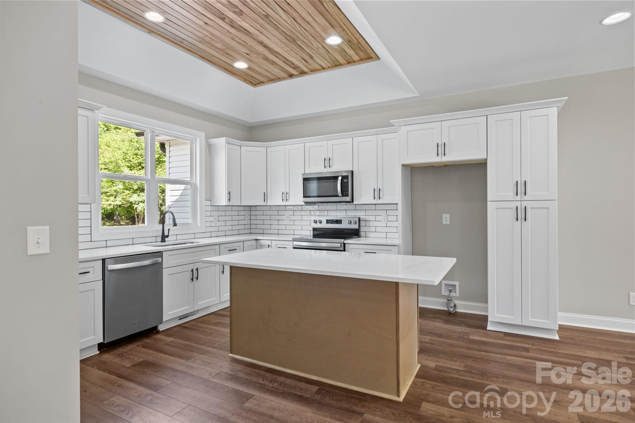 5037 Faith Road Salisbury, NC 28146 - Photo 15 of 45 a kitchen with stainless steel appliances granite countertop a stove top oven a sink dishwasher a refrigerator and a dining table with wooden floor