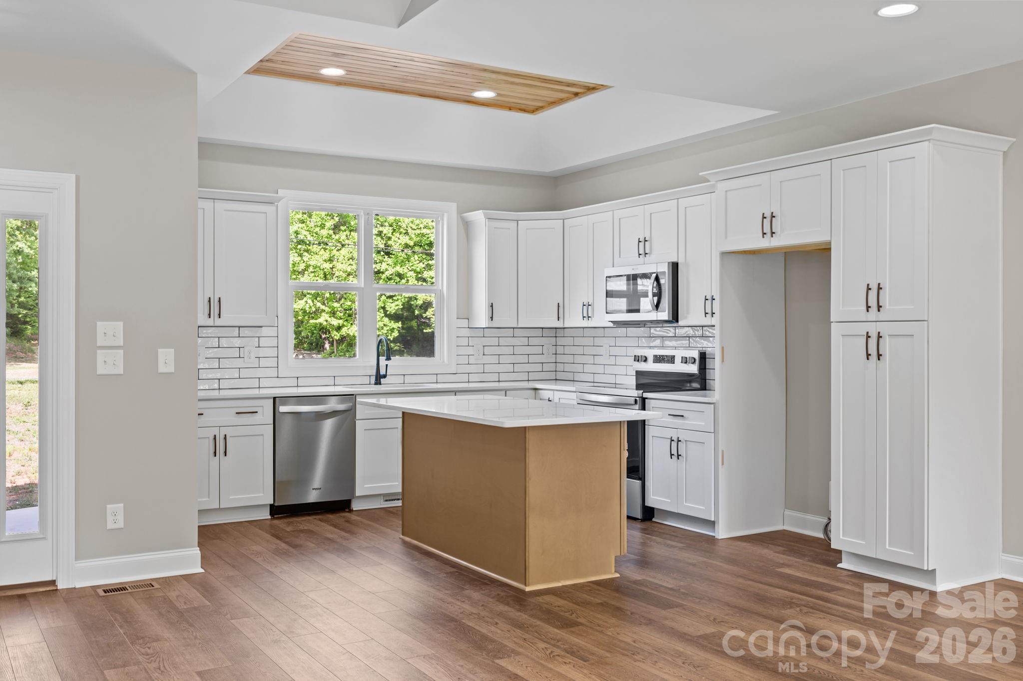 5037 Faith Road Salisbury, NC 28146 - Photo 16 of 45 a kitchen with stainless steel appliances granite countertop a refrigerator a sink dishwasher a stove and white countertops with wooden floor