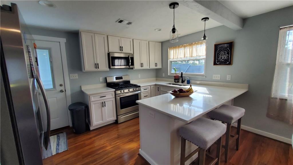 12106 Center Street Irwin, PA 15642 - Photo 10 of 27 a kitchen with stainless steel appliances granite countertop a sink a stove a refrigerator cabinets and a dining table with wooden floor