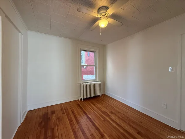 an empty room with wooden floor fan and windows