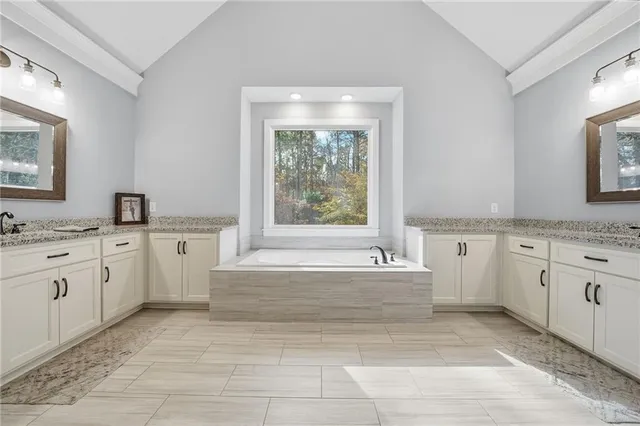 a spacious bathroom with a granite countertop tub sink and mirror
