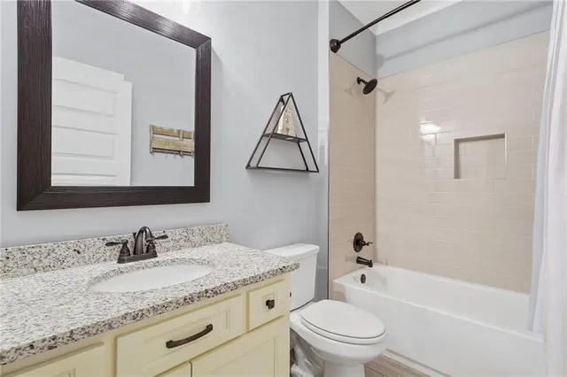 a bathroom with a granite countertop sink a toilet and shower