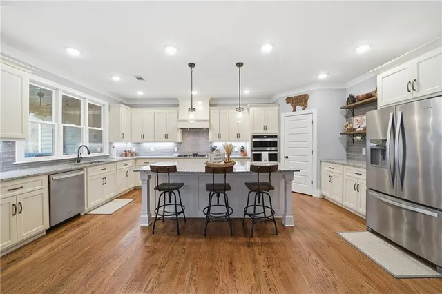 a kitchen with stainless steel appliances a dining table chairs refrigerator and sink