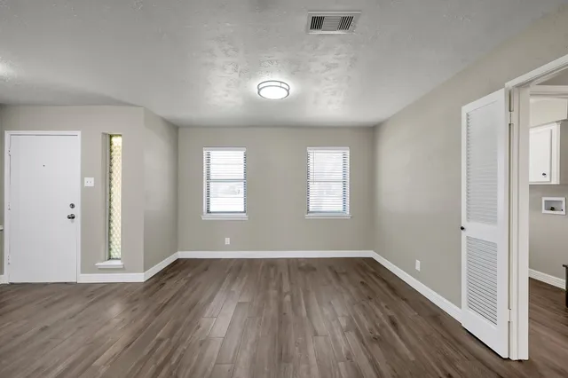 an empty room with wooden floor and windows