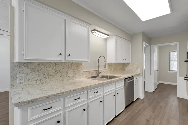 a kitchen with white cabinets and sink