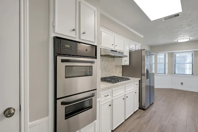 a kitchen with cabinets stainless steel appliances and wooden floor