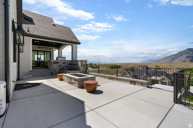 115 East Hidden Ridge Lane, Unit 42 Mapleton, UT 84664 - Photo 83 of 103 Expansive concrete patio featuring a built-in stone fire pit and a stone-clad outdoor kitchen area with integrated grill