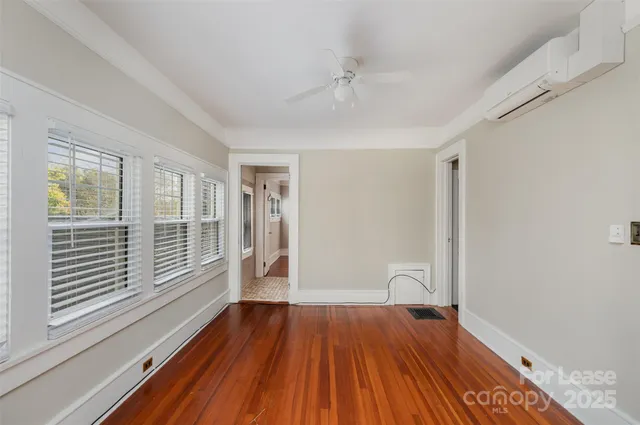 a view of empty room with wooden floor and fan