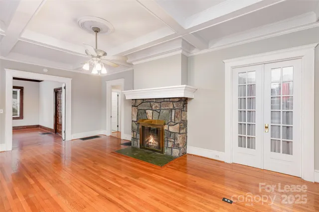 a view of an empty room with wooden floor fireplace and a window