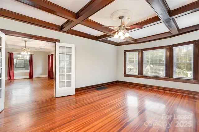 a view of an empty room with wooden floor and a window