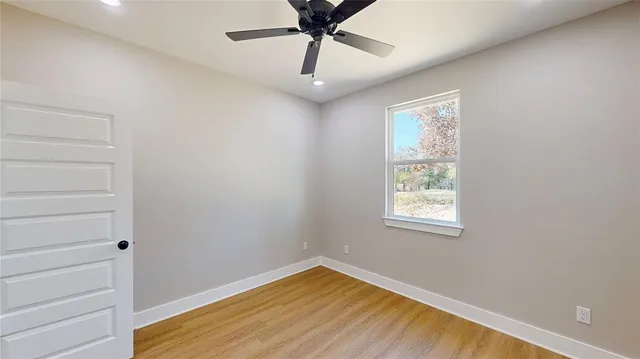 a view of an empty room with a window and wooden floor