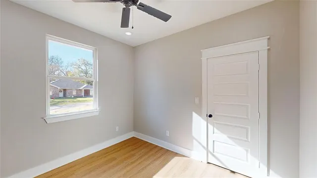 a view of an empty room with window and wooden floor