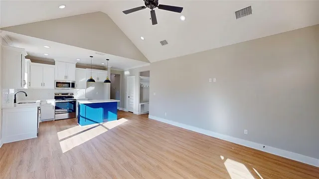 a living room with stainless steel appliances kitchen island granite countertop furniture a rug and a wooden floor