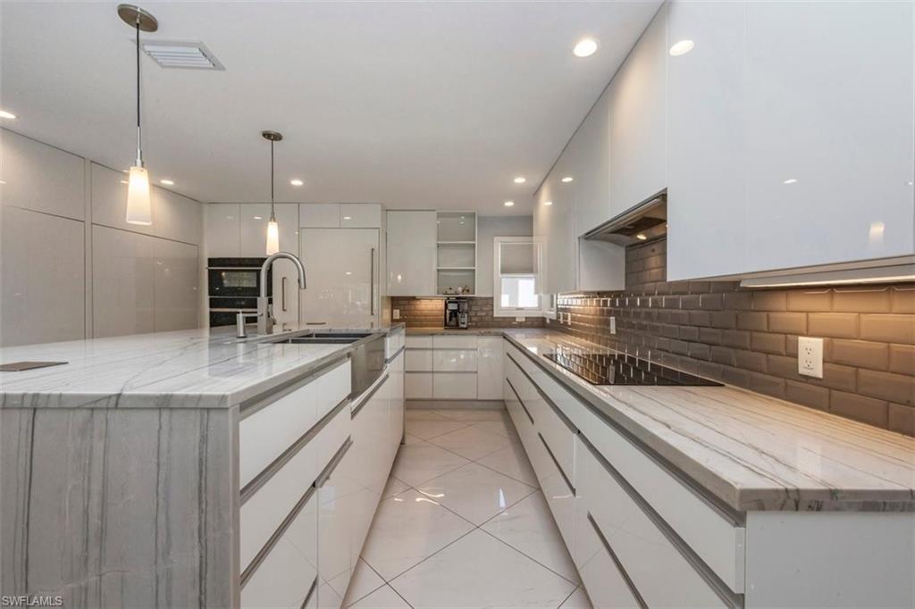 550 Cormorant Cove Naples, FL 34113 - Photo 7 of 39 a large kitchen with a large counter top a sink stainless steel appliances and cabinets