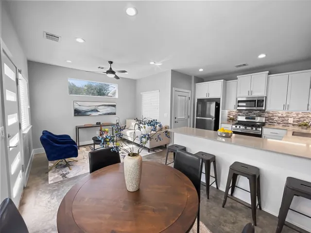 a kitchen with stainless steel appliances granite countertop a stove a sink a dining table and chairs