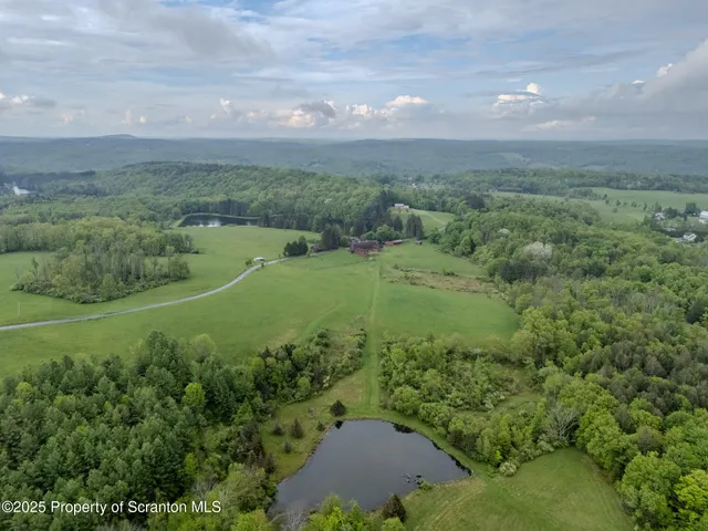 an aerial view of a houses with outdoor space and trees all around