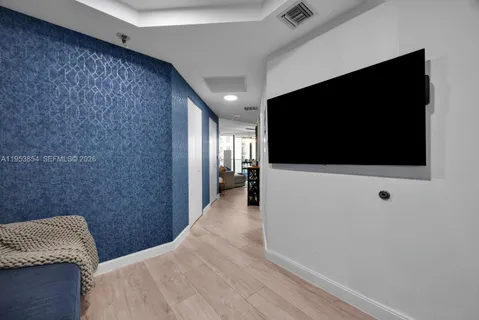 a hallway with a flat screen tv and a refrigerator