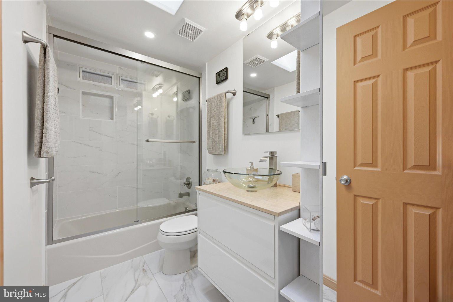 10929 Howland Drive Reston, VA 20191 - Photo 35 of 66 a bathroom with a granite countertop sink toilet a shower and a mirror