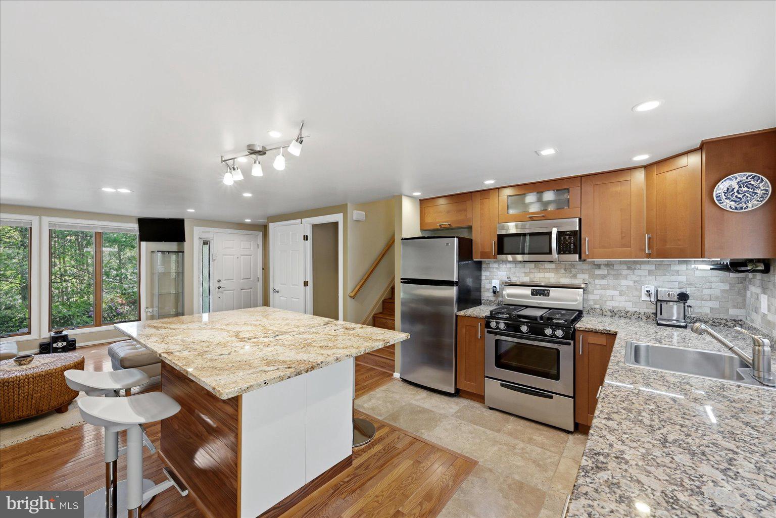 10929 Howland Drive Reston, VA 20191 - Photo 9 of 66 a kitchen with stainless steel appliances granite countertop a stove top oven a sink dishwasher a dining table and chairs with wooden floor