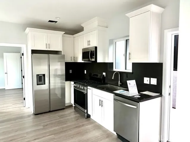 a kitchen with stainless steel appliances granite countertop a refrigerator a stove a sink and a microwave