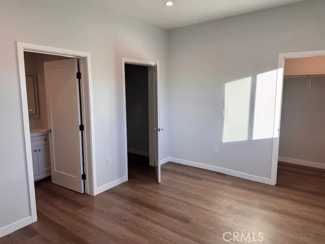 a view of an empty room with wooden floor and closet
