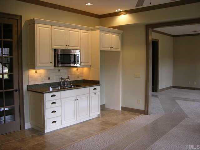 9020 Chelsea Drive Raleigh, NC 27603 - Photo 9 of 10 a kitchen with granite countertop a sink a microwave a refrigerator and cabinets
