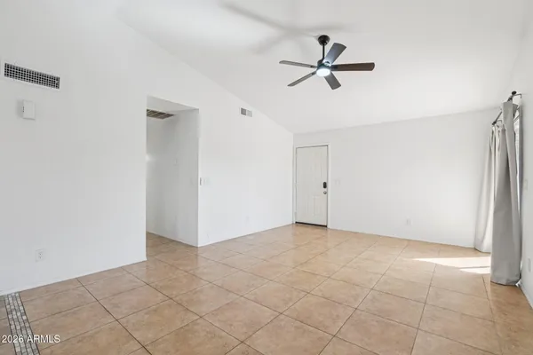 a view of an empty room and chandelier fan