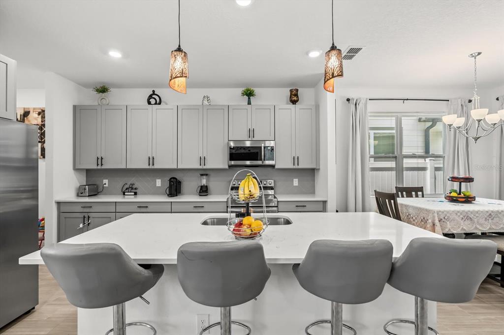 17061 Seville Orange Road Winter Garden, FL 34787 - Photo 4 of 42 a kitchen with stainless steel appliances kitchen island granite countertop a refrigerator and a stove top oven