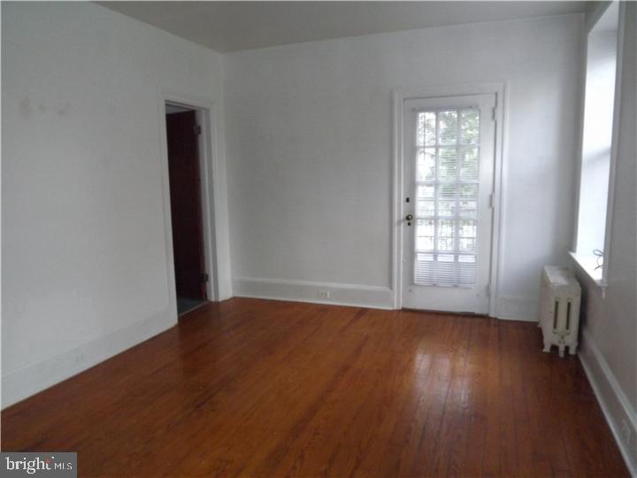 7905 Ardleigh Street, Unit 2 Philadelphia, PA 19118 - Photo 4 of 7 an empty room with wooden floor and windows