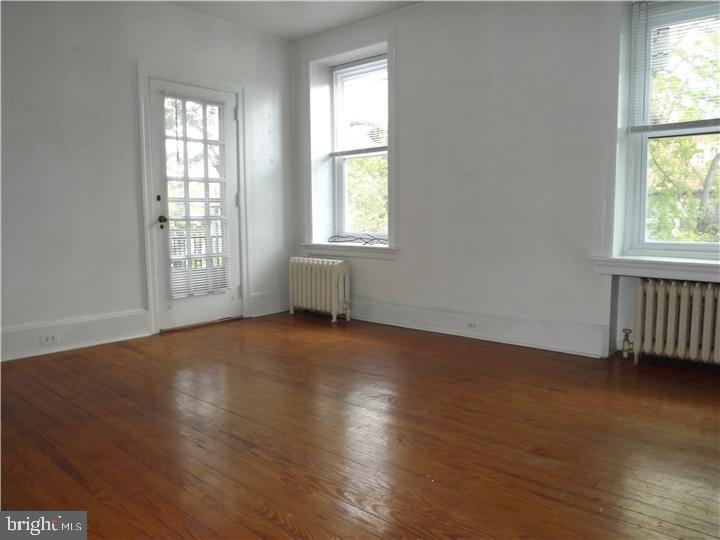7905 Ardleigh Street, Unit 2 Philadelphia, PA 19118 - Photo 5 of 7 an empty room with wooden floor and windows