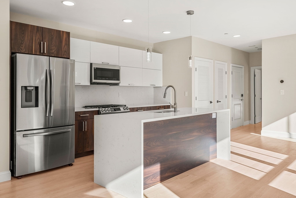 124 Warren Street, Unit 202 Boston, MA 02119 - Photo 4 of 23 a kitchen with stainless steel appliances a refrigerator and a stove top oven