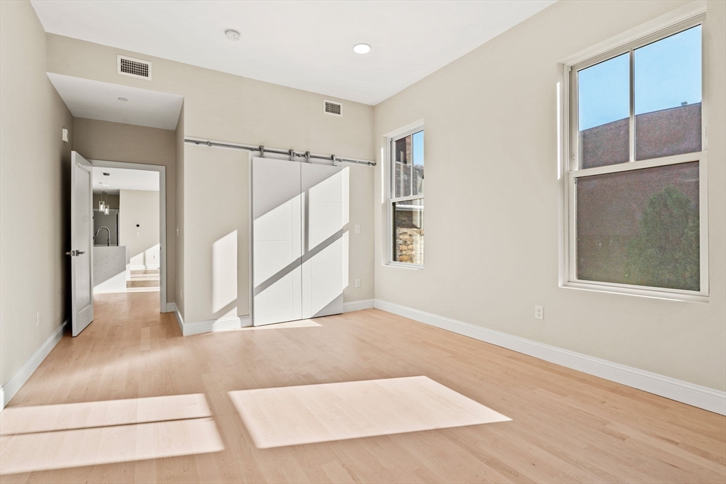124 Warren Street, Unit 202 Boston, MA 02119 - Photo 8 of 23 a view of an empty room with wooden floor and a window