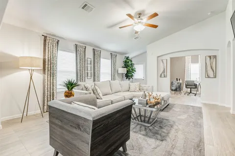 a living room with furniture a large window and a chandelier